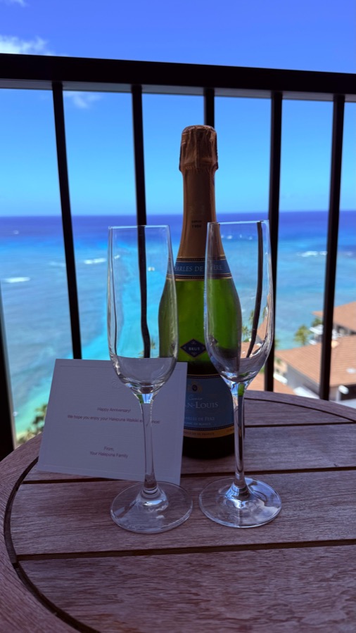 Two champagne flutes and a Happy Anniversary card from Halepuna, Pacific Ocean behind